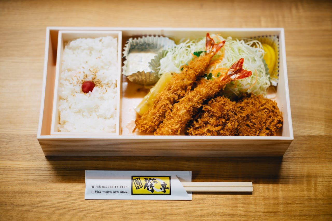 A Japanese bento box featuring rice, prawns, and salad, perfect for lunch or dinner.